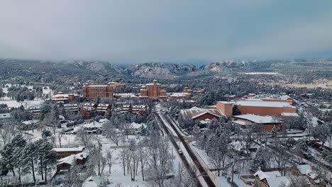 Panoramic-aerial-pullback-above-snow-covered-streets-and-neighborhoods-below-imposing-view-of-destination-hotel-in-Colorado