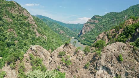 Lush-green-mountains-under-clear-blue-skies,-river-cutting-through-the-valley