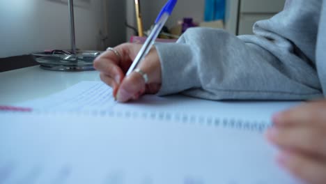 Hand-Einer-Studentin,-Die-Notizen-Auf-Dem-Tisch-Schreibt-Und-Zu-Hause-Aufgaben-Erledigt
