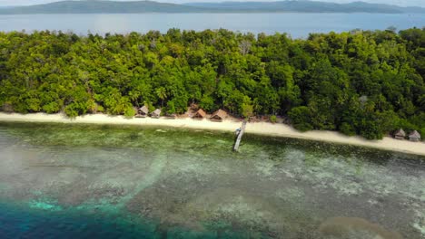 Indonesian-wooden-guest-house-on-sandy-white-beach-in-front-of-blue-lagoon