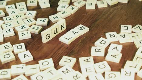Bright-Scrabble-tile-letters-form-words-GUN-and-LAWS-on-wooden-table