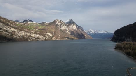 Eine-Drohne-Erhebt-Sich-Langsam-über-Dem-Windgepeitschten-Wasser-Des-Sees-Im-Schweizerischen-Walensee,-Während-Das-Sonnenlicht-Auf-Die-Berge-Scheint