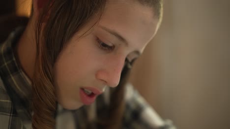 A-jewish-12-year-old-boy-is-sitting-by-a-table-and-writing,-close-up