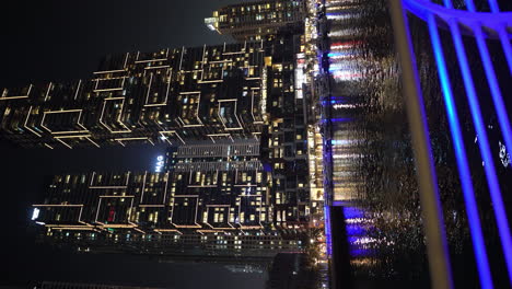 Vertical-Video---Dubai-Marina-at-Night,-Shinny-Buildings-and-Light-Reflection-on-Water-UAE