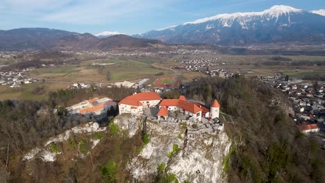 Aerial-parallax-shot-of-Bled-Stronghold-with-forest-and-mountains-at-background-in-Slovenia