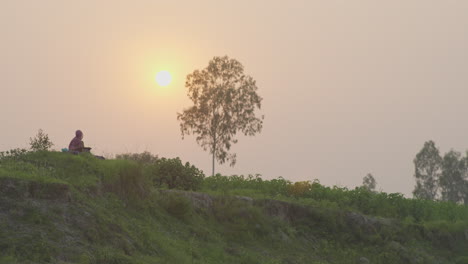 Mujer-Sentada-En-La-Cima-De-Una-Colina-Durante-El-Atardecer