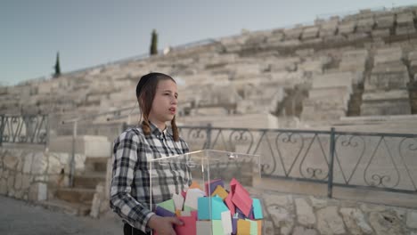 Un-Niño-Judío-De-12-Años-Caminando-En-El-Cementerio-De-Har-Hamenuchot-Hacia-La-Tumba-De-Su-Padre-Con-Una-Caja-De-Papeles-En-Sus-Manos.