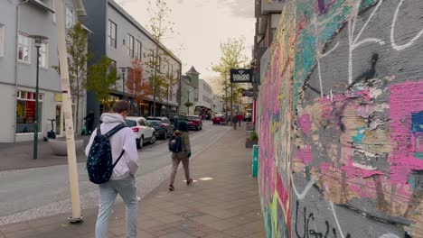 Colorful-graffiti-on-wall-on-Reykjavik-street-with-pedestrians-and-cars,-cloudy-day