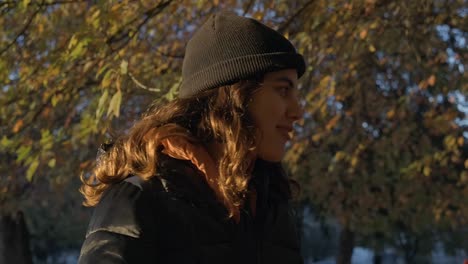 Young-Woman-with-Black-Beanie-Beneath-Tree-in-Fall-Colours-SLOMO-CU