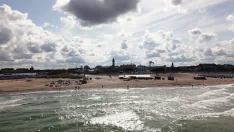 beautiful-beach-with-waves,-lighthouse,-baltic-sea,-warnemünde,-drone