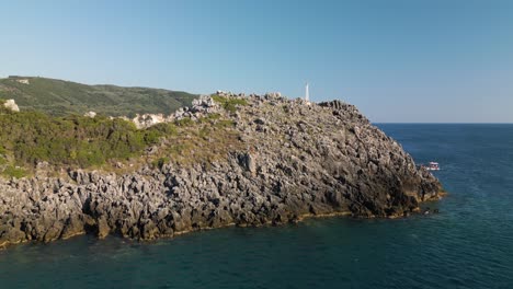 Drone-dolly-to-jagged-rocky-outcropping-rise-to-reveal-stunning-coastal-getaway-of-Corfu-Greece