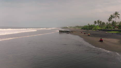 Turistas-Montando-Vehículos-Todo-Terreno-Viajando-Por-La-Playa-De-Arena-En-Bali,-Indonesia