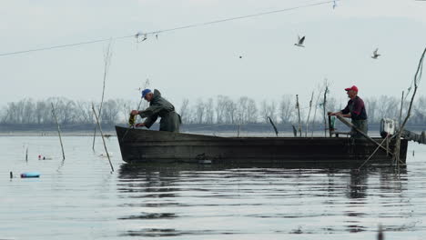 two-Male-Fishermen-on-boat-preparing-fishing-nets-slow-motion-Lake-Kerkini