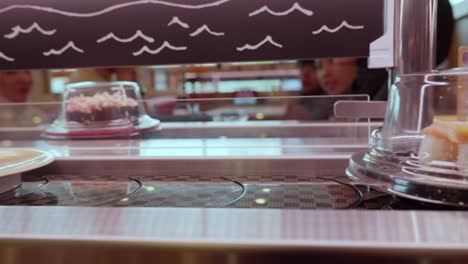 Static-close-up-of-squid-sushi-on-moving-conveyor-belt-in-restaurant