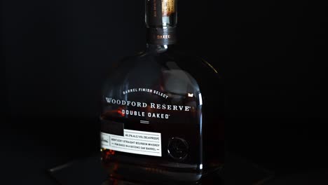Woodford-Reserve-Kentucky-Straight-Bourbon-Whiskey-Doppelt-Eichenholzgelagert-Auf-Einem-Spiegel-Mit-Reflexionen-Und-Einem-Dunkelschwarzen-Hintergrund