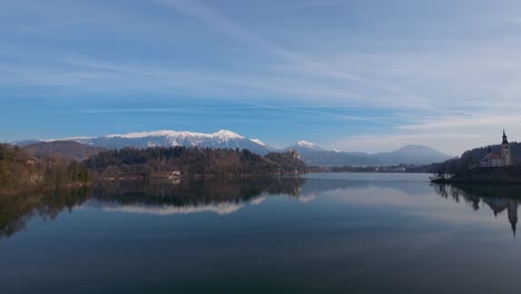 Parallax-shot-of-Bled-lake-with-snow-covered-mountains-at-background-in-Slovenia