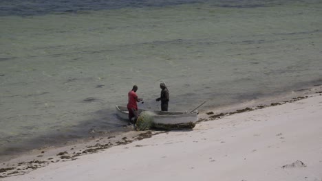 Two-Fishermen-Preparing-Their-Nets-For-Fishing,-Small-Vessel-Boat