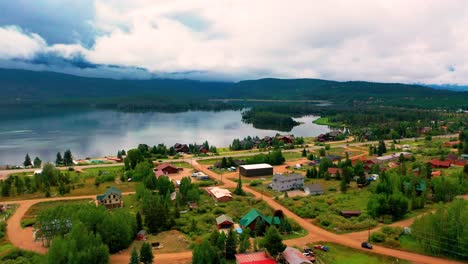 Aerial-Drone-View-of-a-Small-Mountain-Town-Next-to-Grand-Lake-in-Colorado-with-Hills-and-Clouds