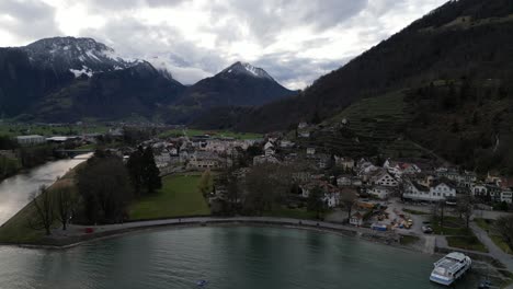 Retirada-Aérea-Desde-La-Orilla-Del-Lago-Con-El-Río-Que-Desemboca-En-El-Valle-De-Walensee,-Suiza