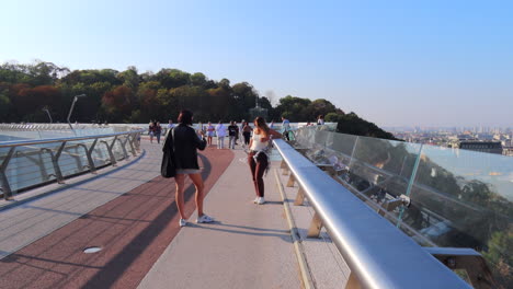 Gente-Caminando-Y-Tomando-Fotos-En-El-Famoso-Puente-De-Cristal-En-El-Centro-De-La-Ciudad-De-Kiev,-Ucrania,-Clima-Soleado-Y-Cielo-Azul,-Puente-Con-Paneles-De-Piso-De-Vidrio,-Tomas-De-4k