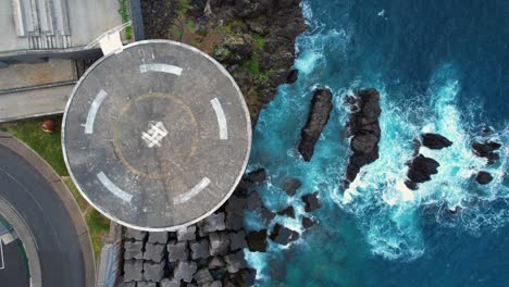 Top-down-view-of-round-Madeira-heli-pad-by-waves-in-azure-blue-ocean