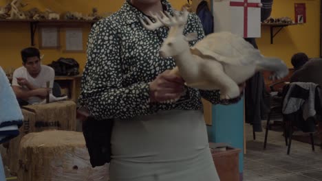 Volunteer-woman-in-a-crafts-workshop-in-Oaxaca-explains-the-process-of-making-traditional-alebrijes-figures-carved-in-wood