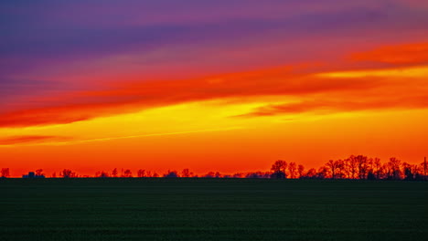 Vibrante-Puesta-De-Sol-Naranja-Sobre-Un-Paisaje-En-Silueta---Lapso-De-Tiempo-De-Paisaje-Nublado