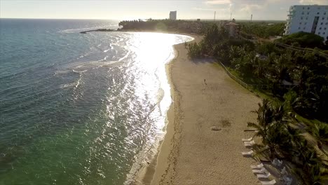 Drone-panning-from-the-right-to-the-left-side-of-the-frame-above-the-beachfront-of-Miami-Beach,-a-popular-getaway-located-in-Central-Greece