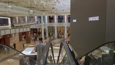 People-shop-inside-shopping-mall-modern-architecture-and-buyers-on-staircase-electric-motion,-stores-at-cape-town-south-africa,-commercial-lifestyle