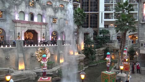 Große-Wasserfontäne-Schießt-Und-Stoppt-Im-Gebäude-Atrium-Während-Der-Weihnachtszeit-Mit-Spielzeugsoldaten-Und-Puppenhaus