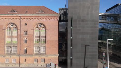 Establishing-drone-riser-shot-of-The-Black-Diamond-Library,-Copenhagen,-Denmark