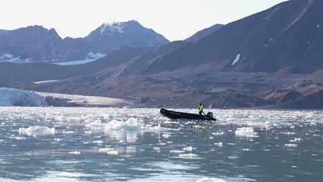 Hombre-En-Barco-Navegando-Entre-Trozos-De-Hielo-Que-Fluyen-En-Un-Lago-Glacial-Bajo-El-Glaciar