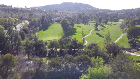 4K-Aerial-View-of-Golf-Course-With-Breathtaking-Mountains-and-Rolling-Hills-in-the-background-in-Los-Angeles,-California-on-a-Warm,-Sunny-Day