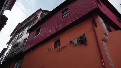 Traditional-Lifestyle-in-Porto,-Portugal:-Locals-Drying-Clothes-on-Colorful-House-Walls-Beneath-Windows-in-a-Quaint-Setting