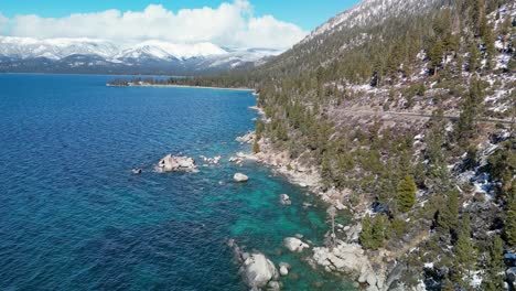 Aerial-view-of-Lake-Tahoe-rocky-shoreline-with-mountains-in-the-distance