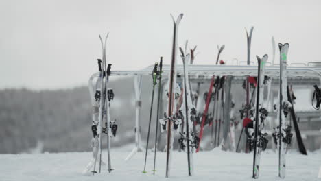 Multiple-skis-on-ski-rack-winter-Christmas-December-janauary-cloudy-gray-snowy-Aspen-Buttermilk-Snowmass-Highlands-AJAX-top-of-Rocky-Mountains-lodge-skier-wilderness-smooth-gimbal-pan-right-slowmotion