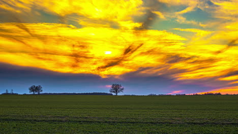 Golden-yellow-sun-behind-giant-clouds-time-lapse-at-sunset-over-grass-field
