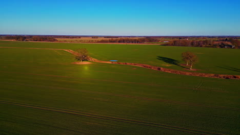 Aerial-drone-forward-moving-shot-over-an-empty-waterway-of-irrigation-system-through-green-farmlands-on-a-sunny-day