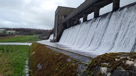 Puerta-De-Barrera-De-Ingeniería-De-Hormigón-De-La-Presa-Cefni-Cubierta-De-Musgo-Que-Vierte-A-Cámara-Lenta-Desde-El-Desbordamiento