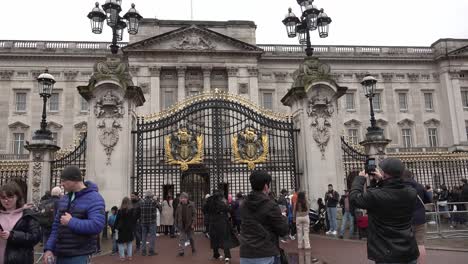 Tourists-take-pictures-at-the-gates-of-Buckingham-Palace-in-London,-UK