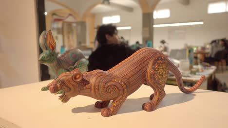 Two-sculptures-carved-in-wood-representing-alebrije-figures,-a-craft-originally-from-Mexico,-displayed-in-a-crafts-workshop