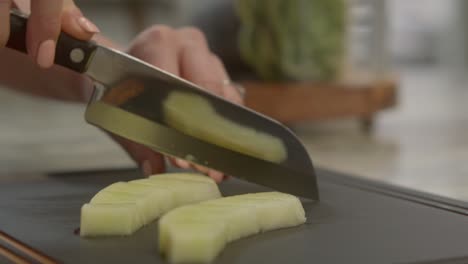 Close-up-of-hands-chopping-up-food-on-a-cutting-board-with-a-very-sharp-and-clean-knife