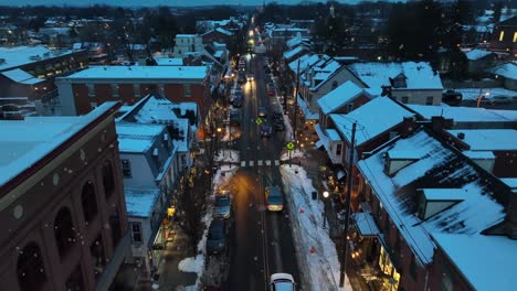 Snowfall-in-American-Town-with-traffic-on-main-street-at-dusk