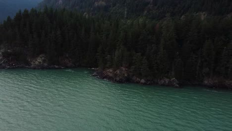 Drone-pulling-away-from-cliff,-with-two-people-sitting-on-the-edge-far-away