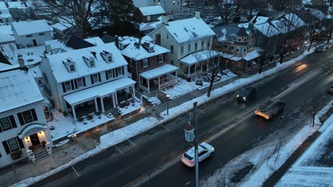 Driving-cars-on-road-at-dusk-in-snow-covered-american-neighborhood