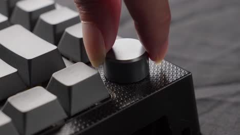 Close-up-of-a-mechanical-keyboard-with-a-distinctive-knob-being-turned,-focus-on-modern-typing-technology