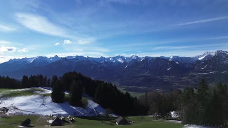 Drone-rise-up-in-sky-and-revealing-amazing-winter-mountain-landscape-with-snowcapped-mountains-on-a-sunny-day-with-blue-sky-in-Austria