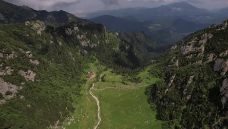 Toma-Aérea-Del-Valle-De-Malaiesti-En-Las-Exuberantes-Montañas-De-Bucegi-Con-Un-Camino-Sinuoso