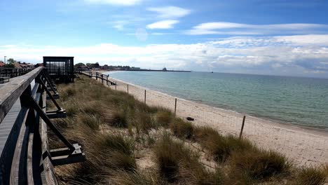 Sunlit-Wooden-Pier-of-sandy-beach-on-Hel-Peninsula,-Baltic-sea,-Pomeranian-Voivodeship,-Poland