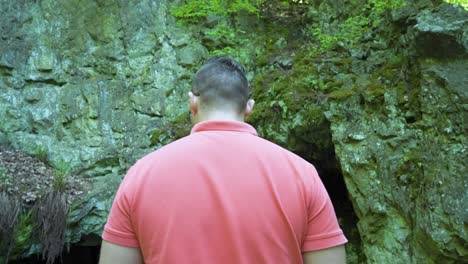 Local-tourist-standing-in-front-of-the-opening-of-cave-known-as-the-site-of-the-tomb-of-the-Egyptian-goddess-Bastet,-located-in-Strandzha-Mountain,-in-Bulgaria